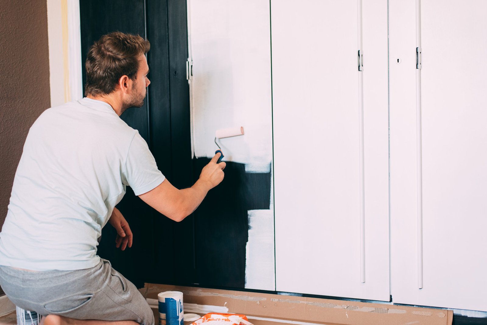 Man painting a wardrobe with a roller